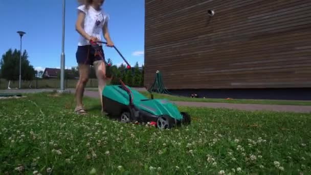 Dziewczyna z kosiarką koszenie trawy w prywatnym podwórku domu. Panorama Gimbala — Wideo stockowe