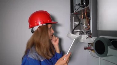 Müfettiş Teknisyen kadın bilgisayarla gaz ısıtma sistemini inceliyor.