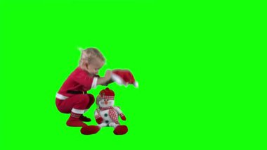 Küçük şirin Noel Baba çocuk Noel Baba şapkasını oyuncak kardan adama taktı.