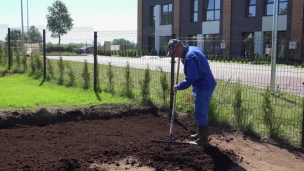 町家の所有者の男は熊手ツールで庭で動作します。土及び堆肥のレベリング — ストック動画