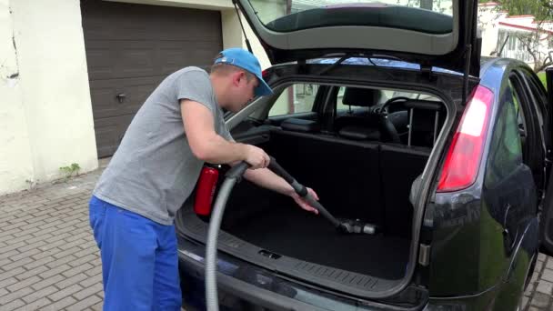 Man hoovering black car boot with vacuum cleaner outdoor. 4K — Stock Video