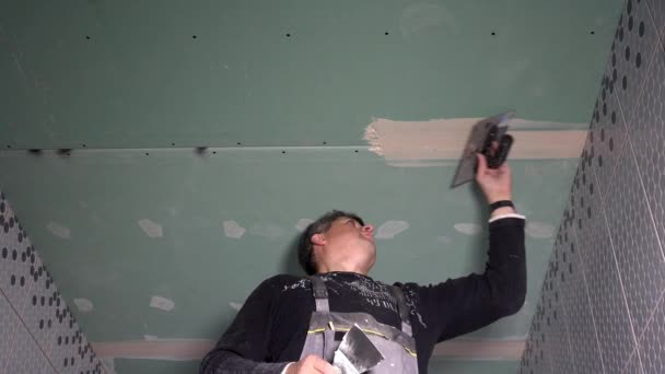 Skilled worker man spackling gypsum plasterboard ceiling with plaster — Stock Video