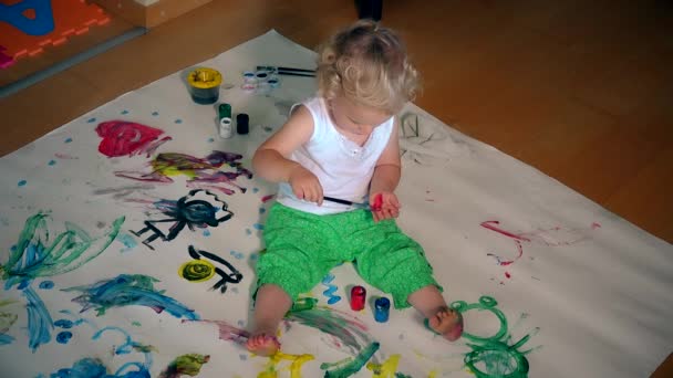 Menina desenhar com escova vermelha na mão. papel no chão. Educação. 4K — Vídeo de Stock