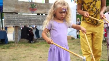 Kadın anne ve küçük kızı büyük sabun köpükleri üflüyorlar.