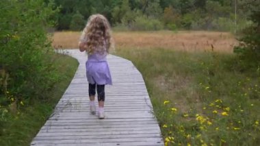 Mor elbiseli küçük cesur kız Tahta yolda tek başına yürüyor