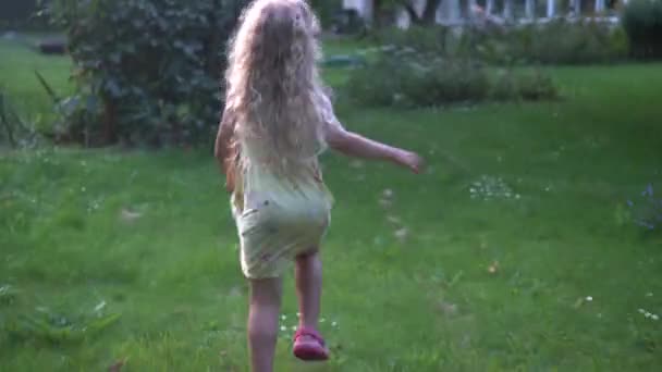 Niña rubia con el pelo rizado corriendo por el prado del jardín de verano — Vídeo de stock