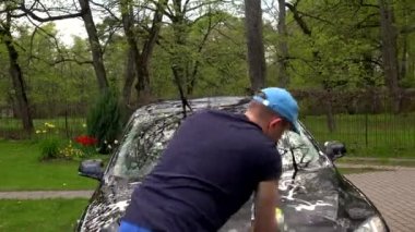 Adam dışarıda köpük süngerle kendi arabasının ön camını yıkıyor. 4K