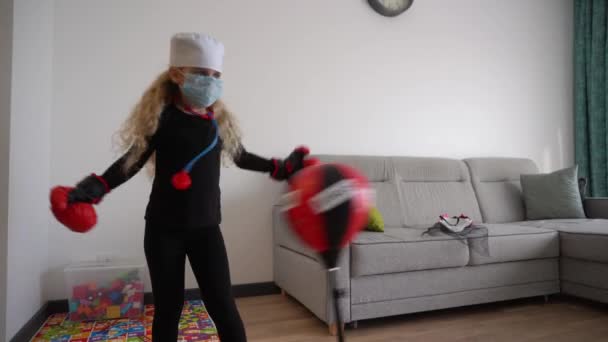 Criança com máscara médica protetora batendo bola de perfuração com vírus de texto nele . — Vídeo de Stock