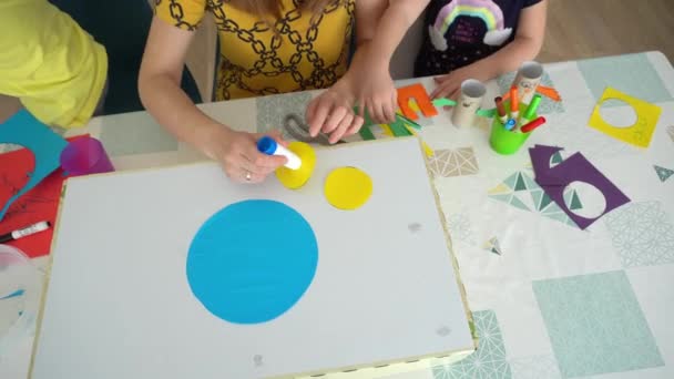 Profesor con niños sentados a la mesa y haciendo cosas hechas a mano . — Vídeos de Stock