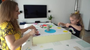 Anne ve sarışın çocuk masada oturmuş oyun oynuyorlar.