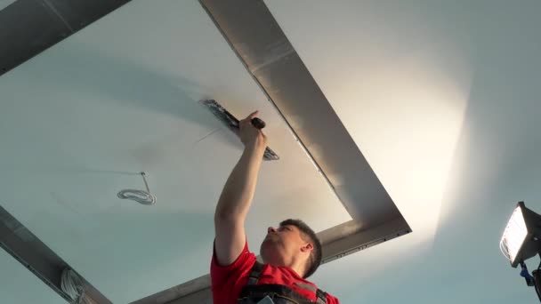 Hombre pintor aplicar relleno de yeso en el techo entre nichos para la iluminación — Vídeos de Stock