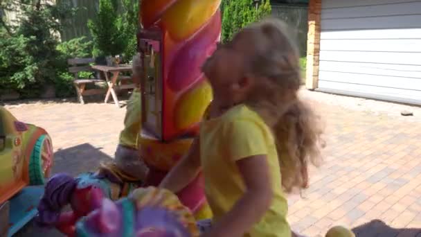 Cute sister and brother sitting on playground carousel. Gimbal motion — Stock Video