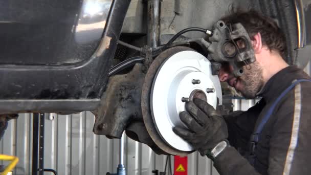 Hombre reparador de coches de trabajo en el disco de freno de coche en la estación de servicio. 4K — Vídeos de Stock