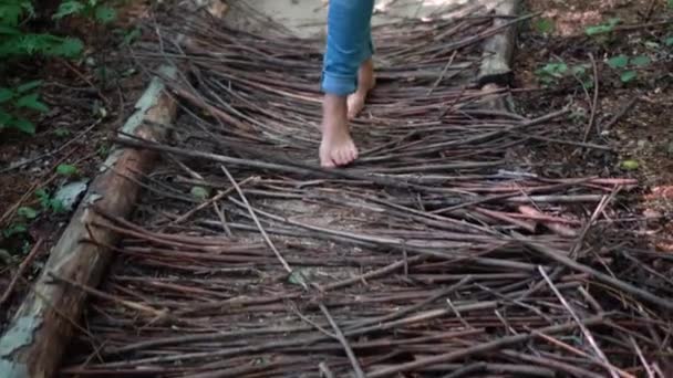Barefoot vrouw voeten in jeans lopen op hout stokken pad. Natuurlijke massage — Stockvideo