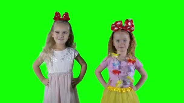 Roodharige en blonde meisjes die voor de camera springen. groene achtergrond. — Stockvideo