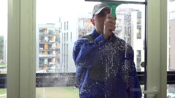 Hombre trabajador limpiar la ventana sucia con limpiaparabrisas de limpieza de vidrio. 4K — Vídeo de stock