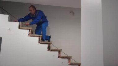 Marangoz merdiveni metreyle ölçer. Yeni merdiven kurulumu çalışmaları