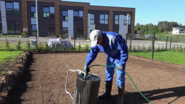 Paisajista hombre llenando suelo tierra rodillo con agua de la manguera. Disparo estático — Vídeo de stock