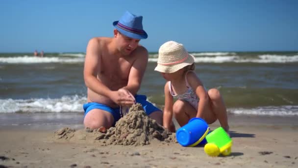 Pai amoroso e filha menina brincando junto com a areia na costa do mar — Vídeo de Stock