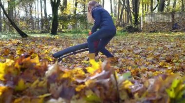 Ev hanımı bahçede yaprak üfleme makinesiyle renkli yapraklar üflüyor.