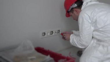 Elektrikçi adam çerçeveleri prizlere vidalıyor. 4K