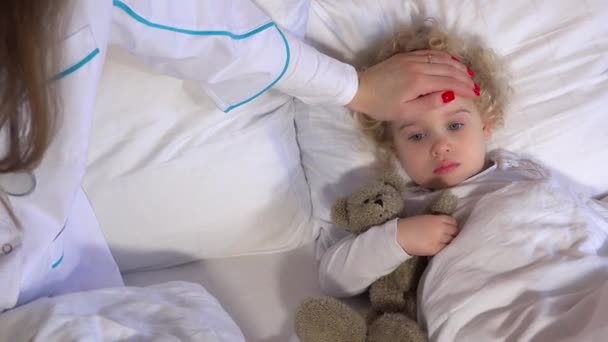 Malá nemocná, horečnatá dívka ležící v posteli s pečovatelskou péčí v ložnici. 4K — Stock video