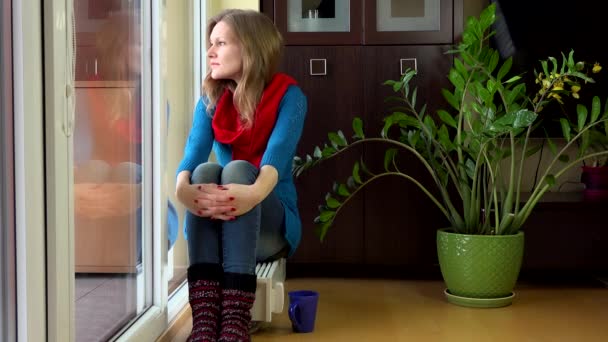Mujer sentarse en el radiador cerca de la ventana con taza de té sala de estar. 4K — Vídeos de Stock