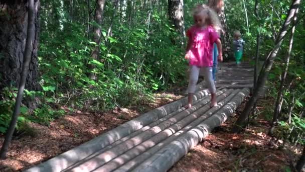 Barefoot family mother with son and daughter walking on tree trunk logs pathway — Stock Video