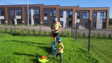 Küçük oğlu da tıpkı babası gibi çim biçme makinesiyle çim biçiyor. Gimbal hareket et