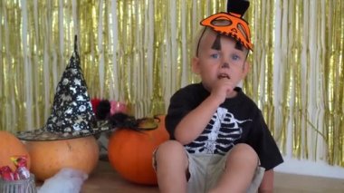 Süslü giysiler içinde balkabağıyla odada oturan sevimli çocuk portresi.