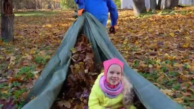 Neşeli bir adam hızla kızını çekiyor ve sonbahar yaprakları çadırda uzanıyor.