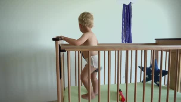 Hyperaktivní chlapeček v postýlce. Samotné dítě se baví v posteli. Gimbalův pohyb — Stock video