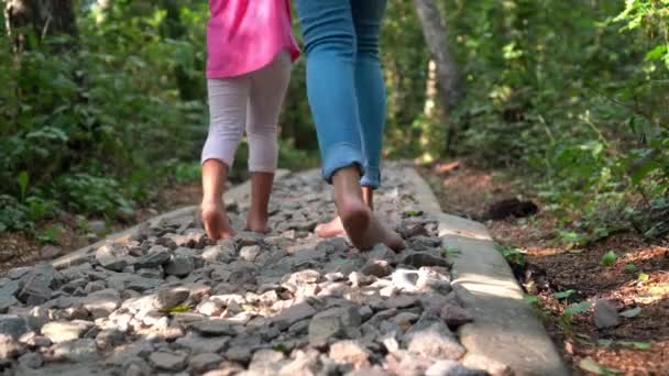 Maman avec sa petite fille marchant à travers un chemin rugueux avec de petites pierres — Video