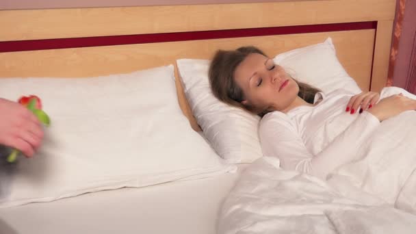 Wanita tidur di tempat tidur dari kain linen putih dan tangan meletakkan bunga tulip di bantal. 4K — Stok Video