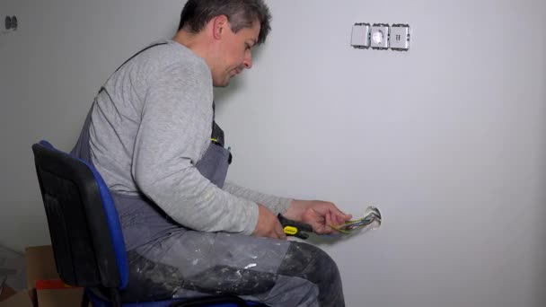 Homme enlevant l'isolation du fil avec un outil de décapage. Électricien connectant les rosettes — Video