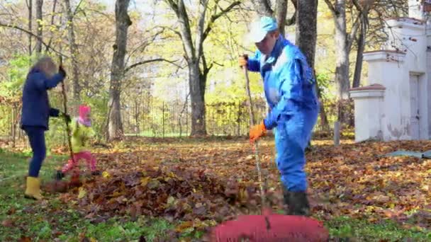 Felice padre di famiglia madre e figlia si divertono mentre rastrellano le foglie — Video Stock