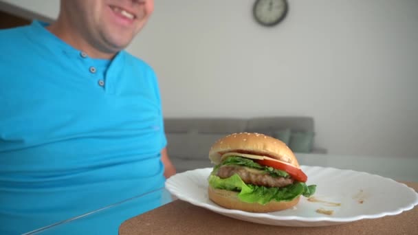 Голодный человек ест жирные гамбургеры быстрого питания. Парень ест гамбургер. Движение камеры крупным планом — стоковое видео