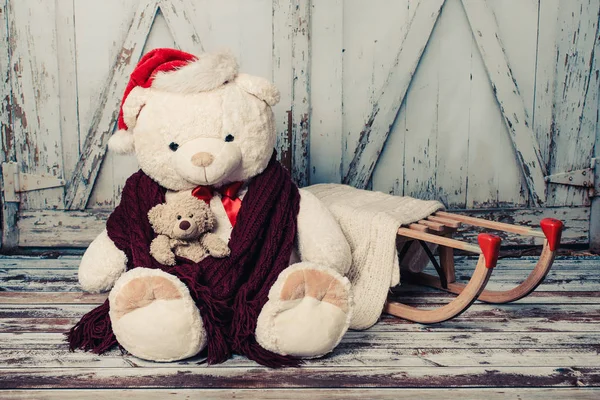 Dois ursos de pelúcia com chapéus de Natal no fundo do portão de madeira Fotografia De Stock