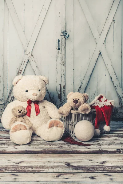 Three teddy bears with Christmas hats on wooden gate background, vintage