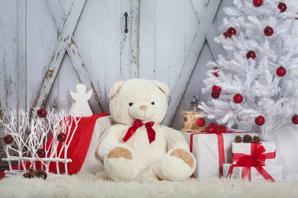 Urso de pelúcia com um anjo e os presentes sentados no fundo do portão vintage de madeira. Árvore Natal Fotografias De Stock Royalty-Free