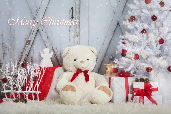 Urso de pelúcia com um anjo e os presentes sentados no fundo do portão vintage de madeira. Árvore Natal Fotografias De Stock Royalty-Free