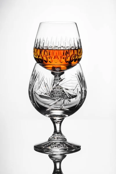 Хрустальные бокалы с ромом, графин с виски на стеклянном столе, белый фон — стоковое фото