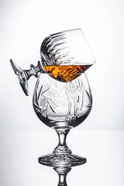 Kristallgläser mit Rum, Karaffe mit Whisky auf einem Glastisch, weißer Hintergrund — Stockfoto