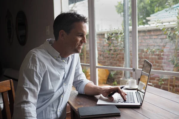 Man smiling while reading computer screen, home office