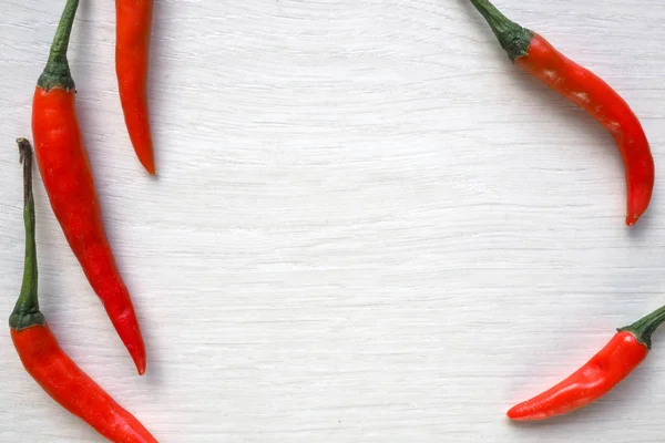 Chilli peppers on white wood background