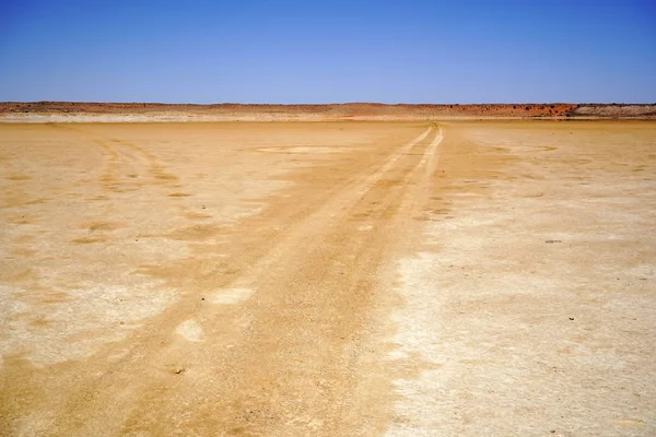 Hosszú földút a sivatagon át a távolba — Stock Fotó