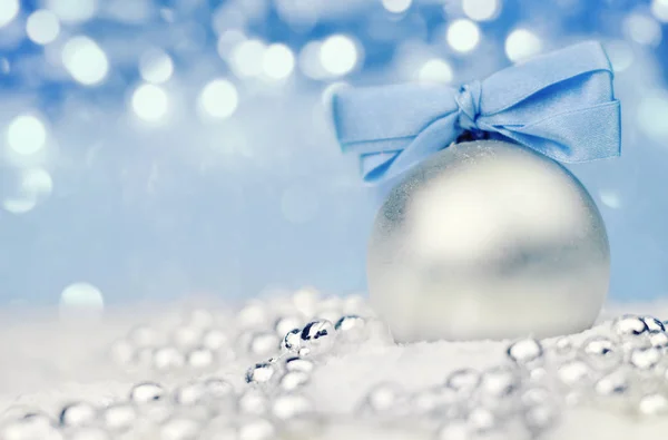 Ασημί Χριστουγεννιάτικη μπάλα σε γυαλιστερό φόντο με μπλε κορδέλα — Φωτογραφία Αρχείου