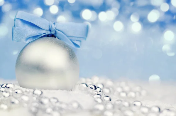 Ασημί Χριστουγεννιάτικη μπάλα σε γυαλιστερό φόντο με μπλε κορδέλα — Φωτογραφία Αρχείου