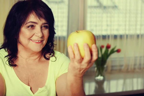 Portrait of happy mature woman with apple — Stock Photo, Image