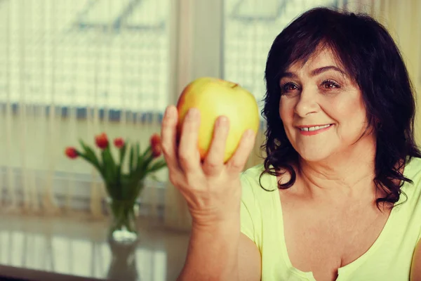 Portrait of happy mature woman with apple — Stock Photo, Image